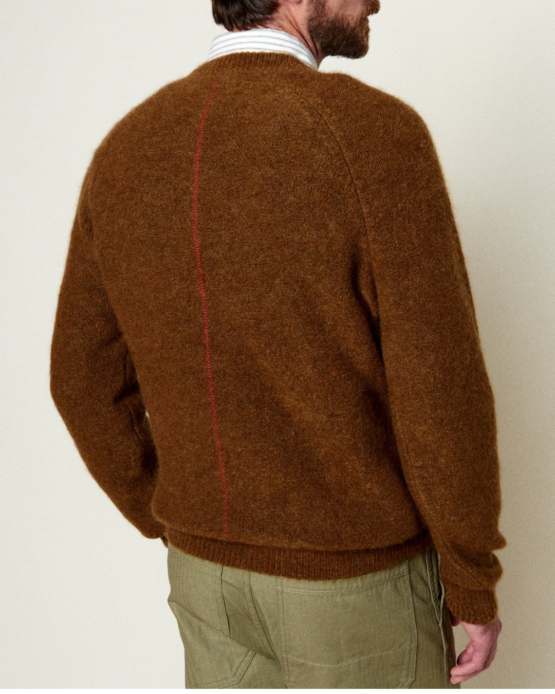 Homme portant un pull Homecore en alpaga marron coffee avec une couture rouge distinctive au dos, vue de dos