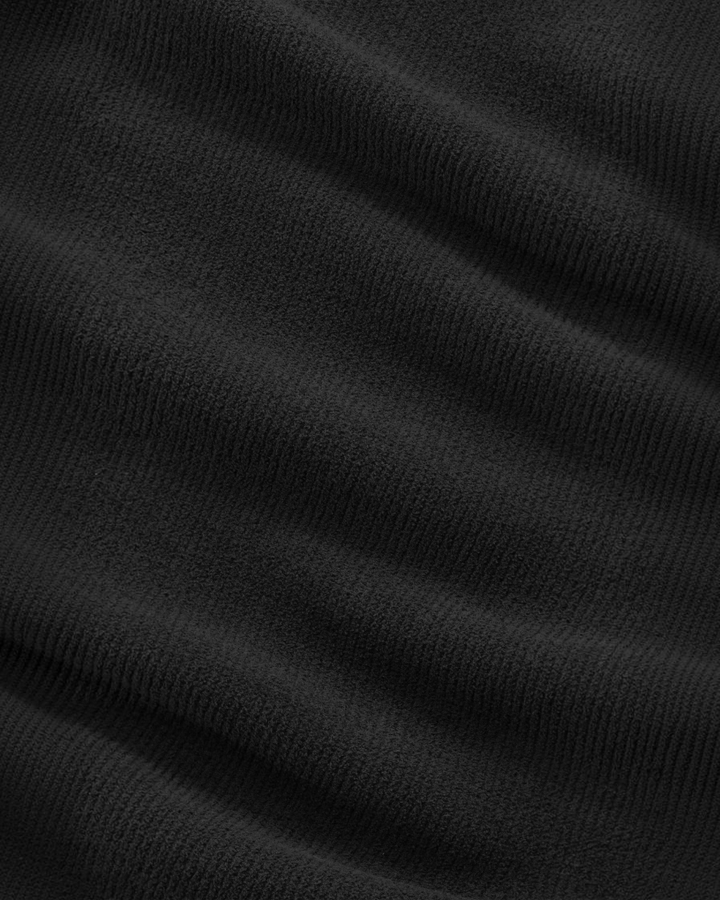 Gros plan sur la maille chenille noire du pull Danny de Merci Paris, texture veloutée et côtelée douce au toucher.