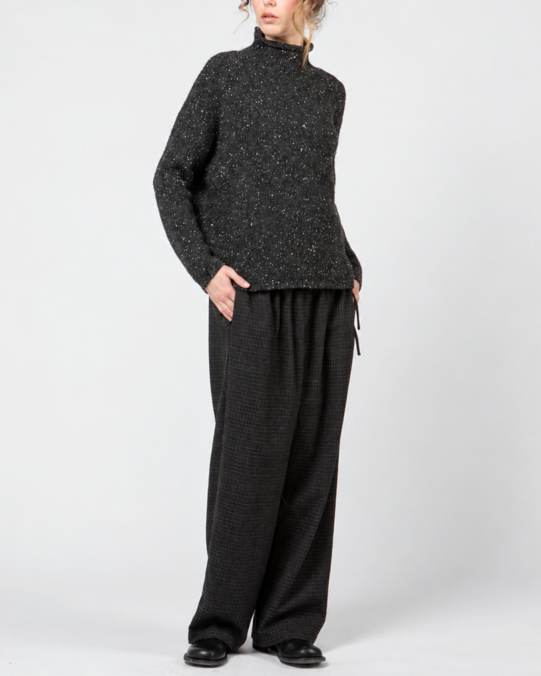 Modèle portant un pantalon large Merci Paris Apuntob bleu marine en laine à carreaux discrets et un pull texturé