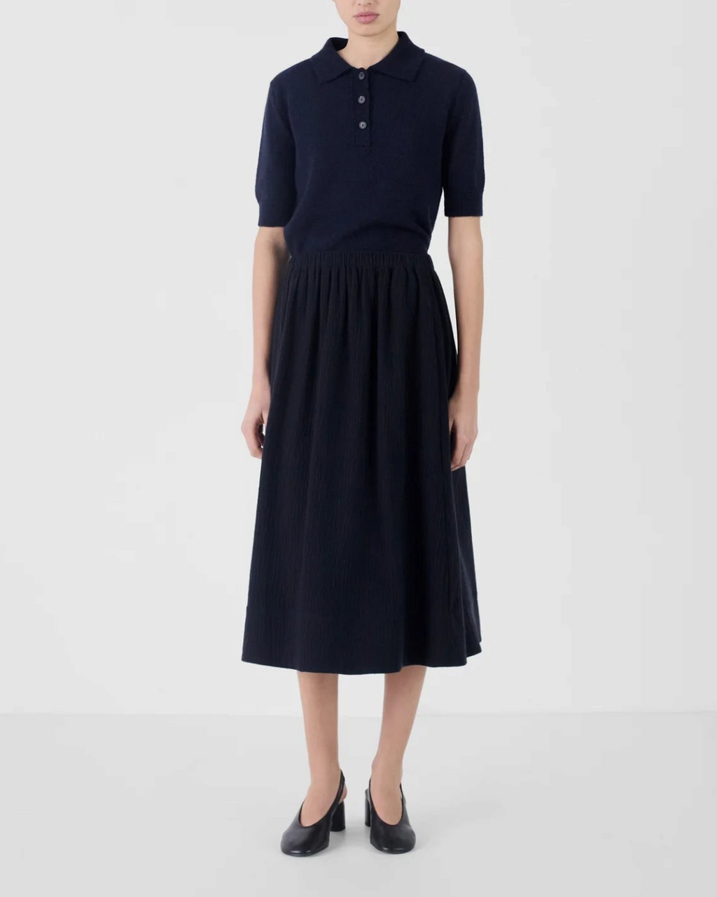 Mannequin portant la jupe midi bleu marine Adele de Merci Paris, en mélange de coton et laine à la coupe froncée.