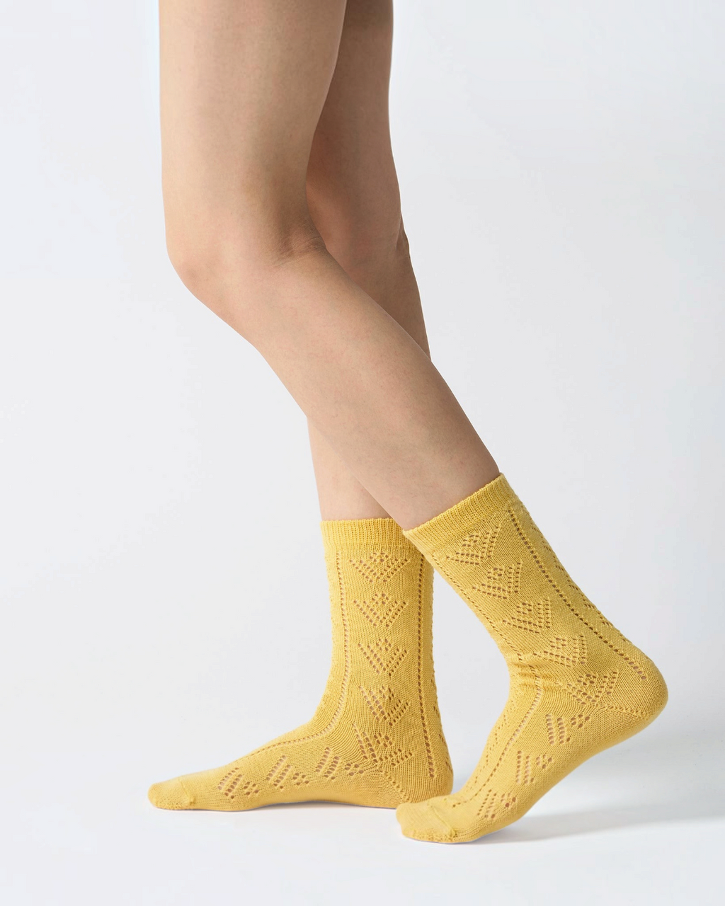 Chaussettes ajourées jaunes Babaco en laine portées, style féminin et artisanal, disponibles chez Merci Paris