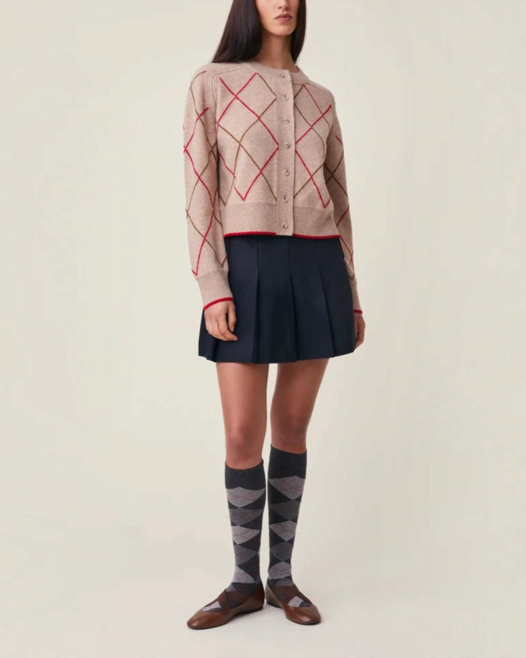 Gilet Auguste Moismont en laine mérinos beige à motif losanges rouges porté par une femme chez Merci Paris