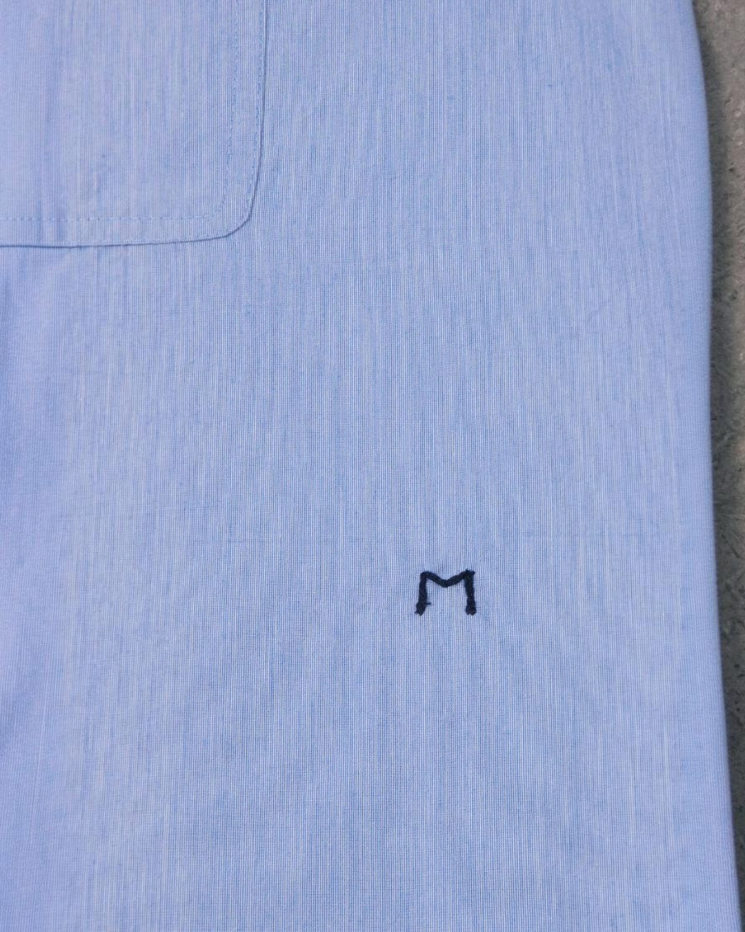 Gros plan sur la chemise Henriette Merci Paris en coton bleu clair avec broderie M signature