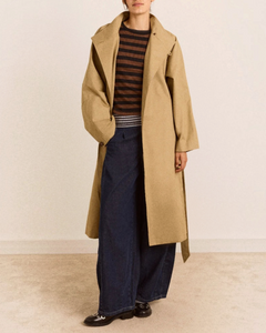 Trench beige mi-long Damson Madder en coton biologique avec col montant, porté par une femme sur fond neutre