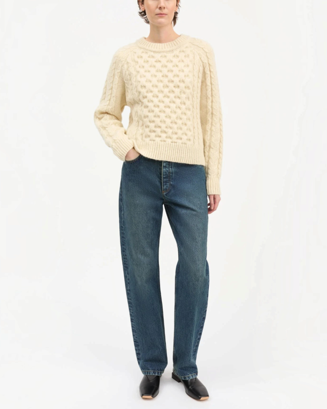 Pull Lennox blanc en laine à maille torsadée Merci Paris porté par une femme avec un jean bleu