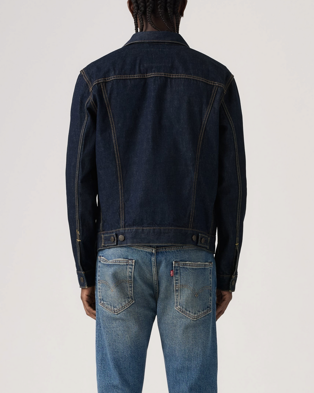 Vue arrière d'un homme portant une veste Trucker Levi's en denim bleu brut avec surpiqûres contrastées chez Merci Paris