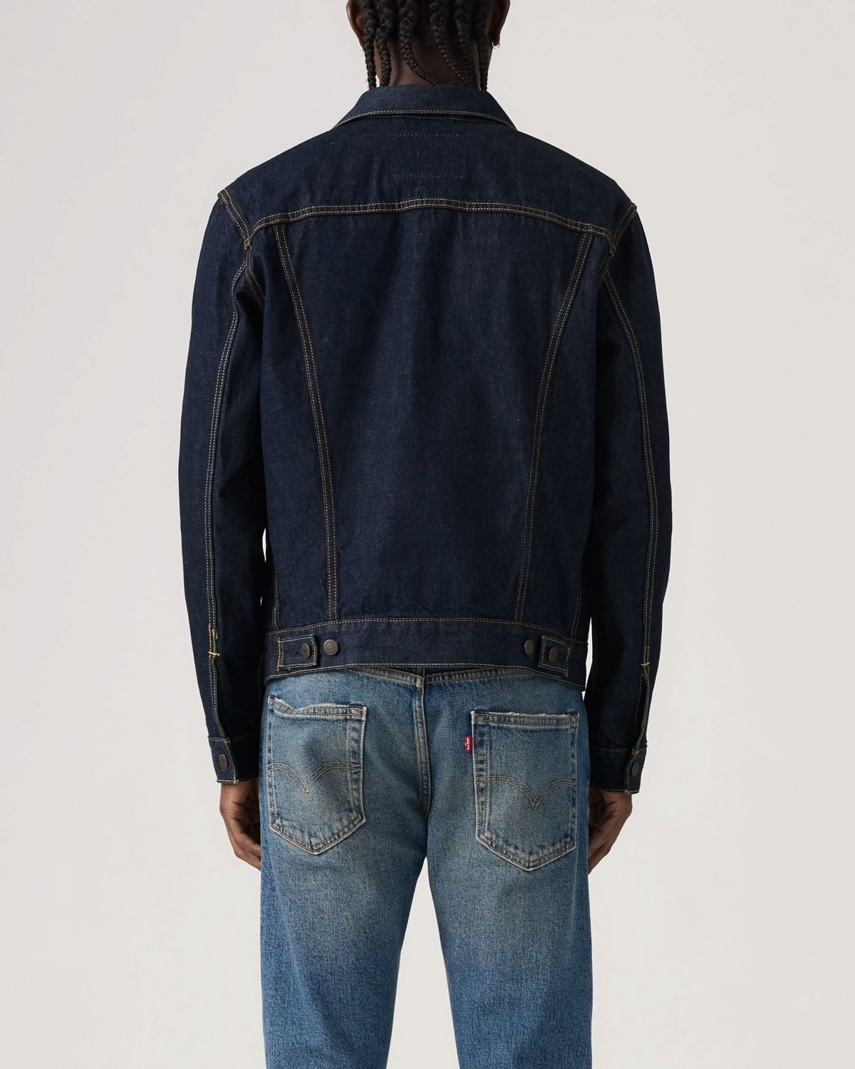 Vue arrière d'un homme portant une veste Trucker Levi's en denim bleu brut avec surpiqûres contrastées chez Merci Paris