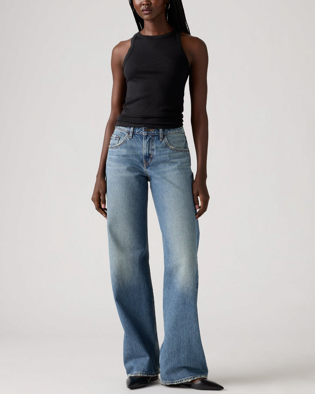 Modèle portant le jean Levi's Low Loose bleu délavé coupe large taille basse avec un débardeur noir Merci Paris