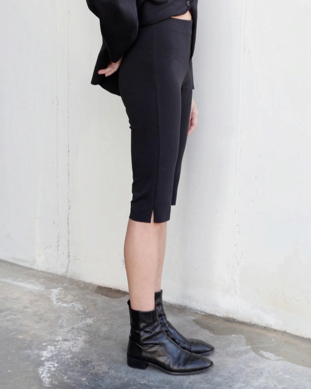 Bermuda noir en maille Merci Paris, coupe ajustée et extensible, porté par un mannequin avec des bottines en cuir.