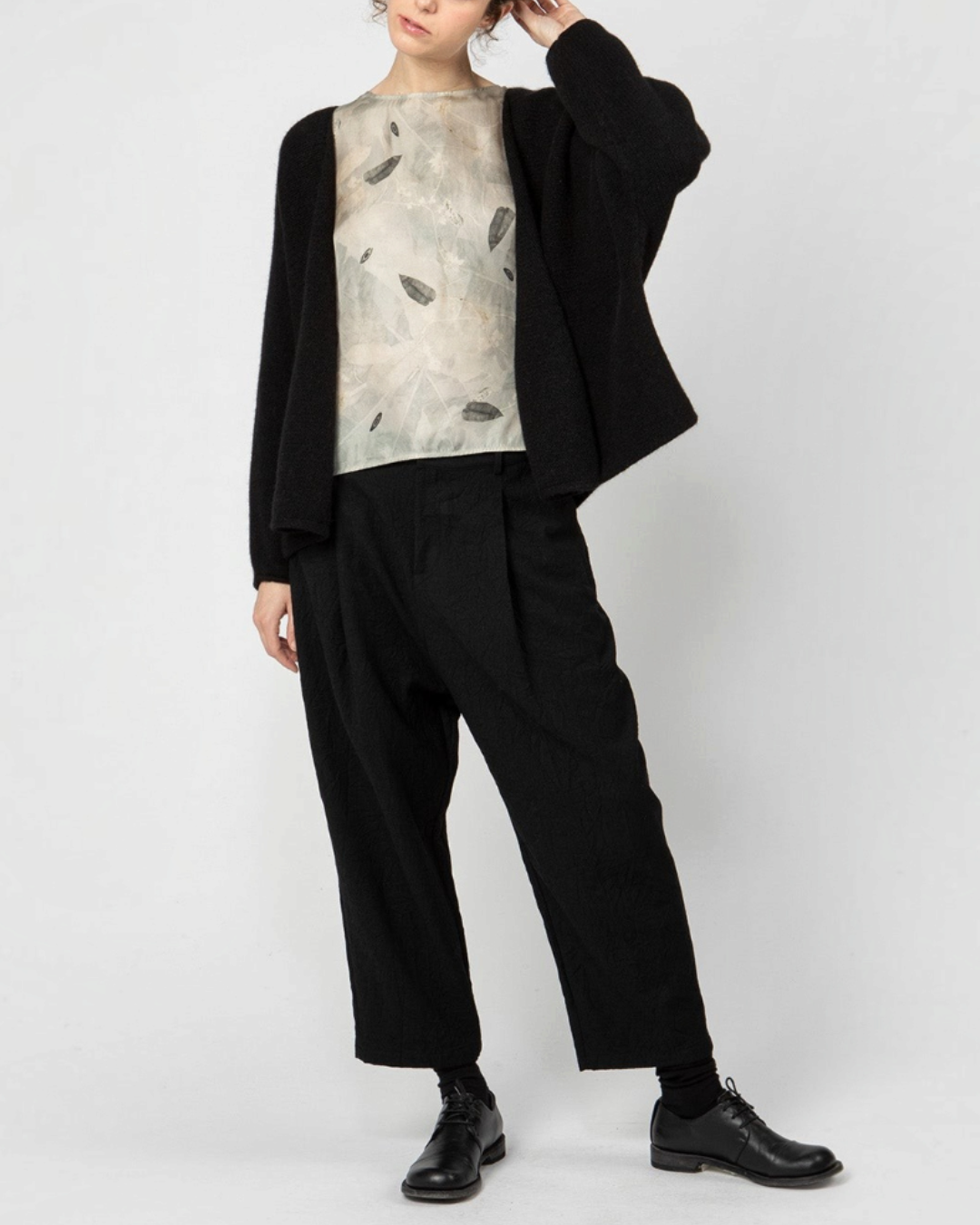 Modèle portant un pantalon 7/8 noir Merci Paris Apuntob à coupe ample, taille à pinces et entrejambe bas
