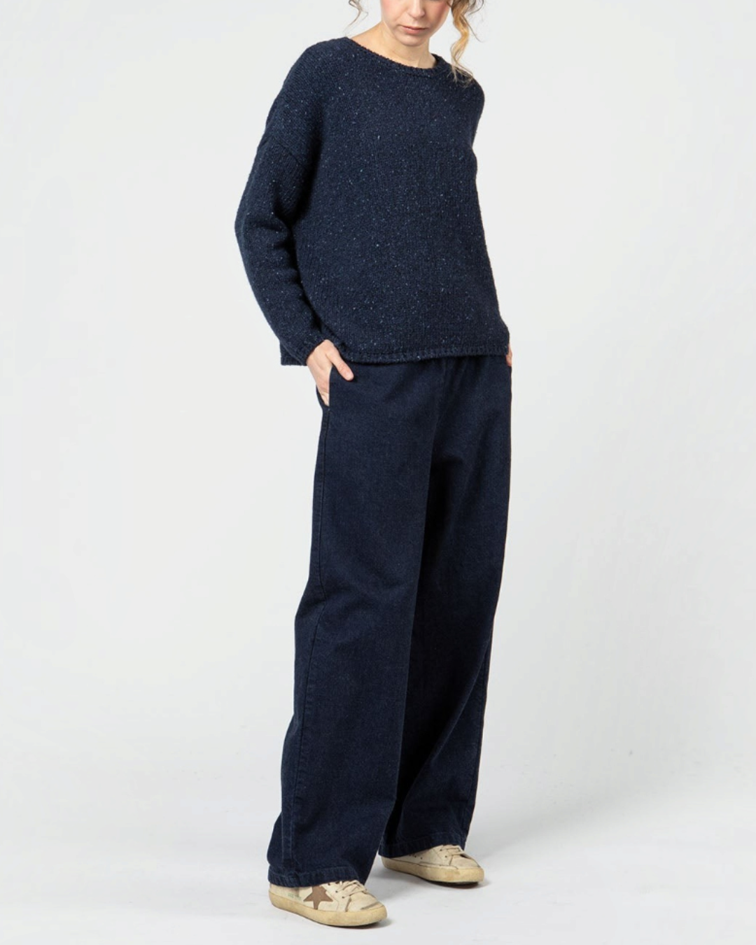 Femme portant un pantalon denim bleu indigo Merci Paris à coupe ample avec taille élastiquée et un pull bleu marine