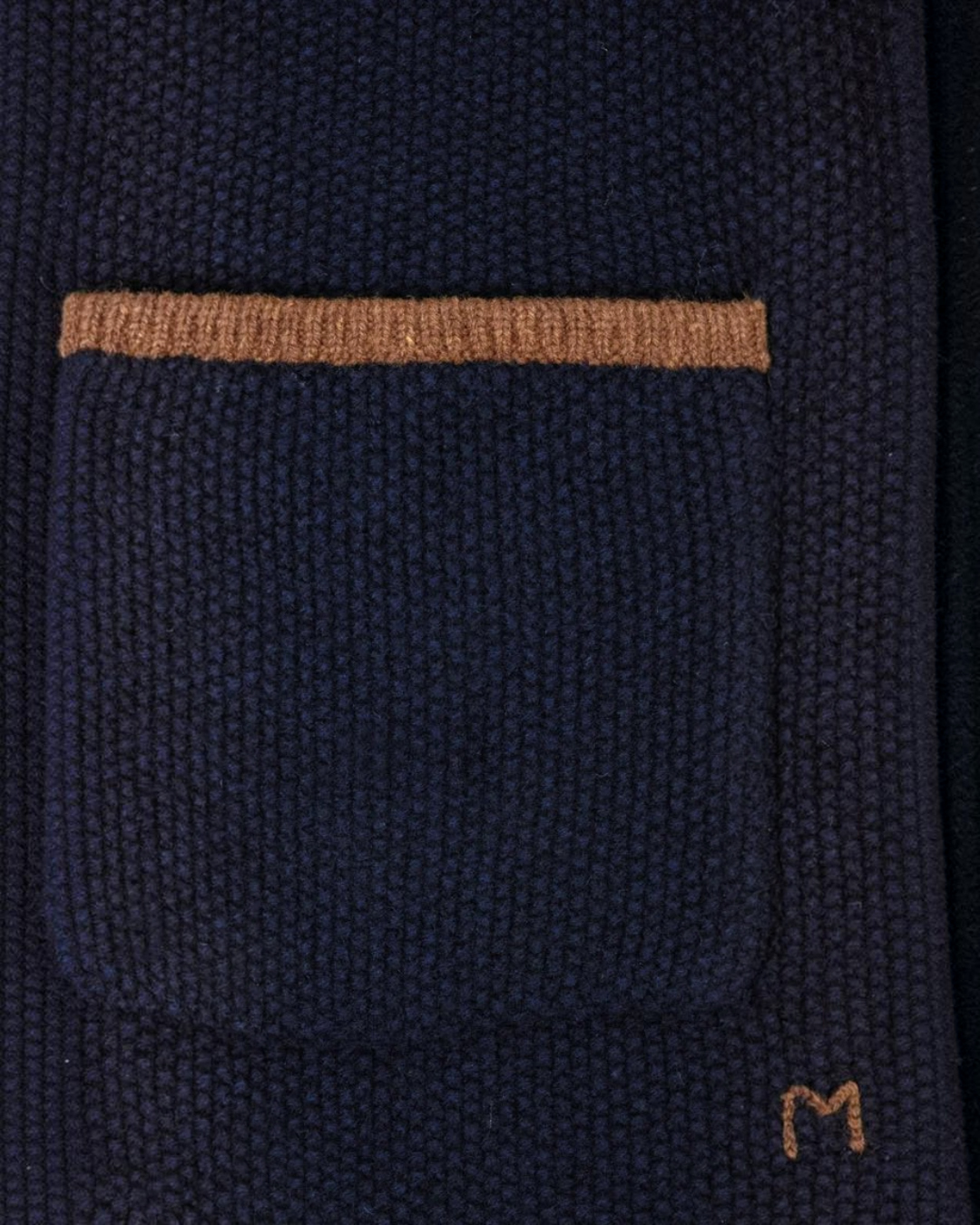 Gros plan sur la poche plaquée du gilet Angele Merci Paris en laine mérinos bleu marine avec bordure contrastée camel