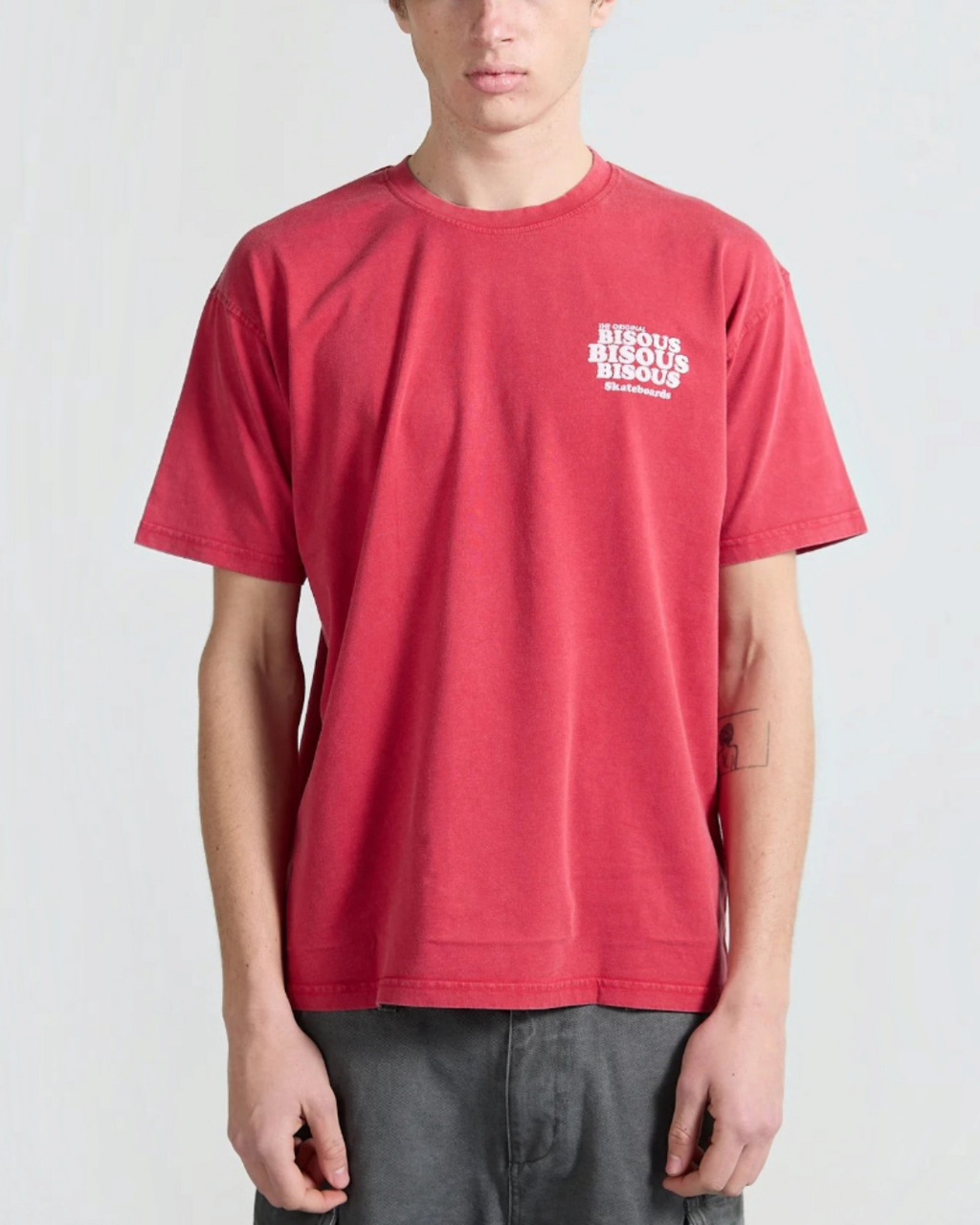 Homme portant un t-shirt Merci Paris Bisous Skateboard rouge délavé en coton avec logo blanc sur la poitrine