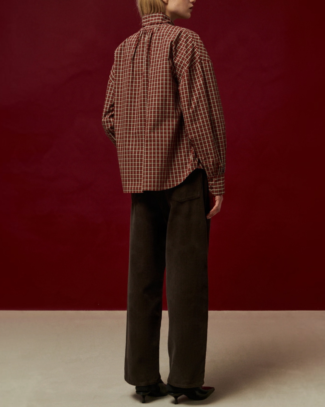 Modèle de dos portant la blouse Merci Paris Belle Pièce Tom en coton à carreaux couleur épice sur fond bordeaux