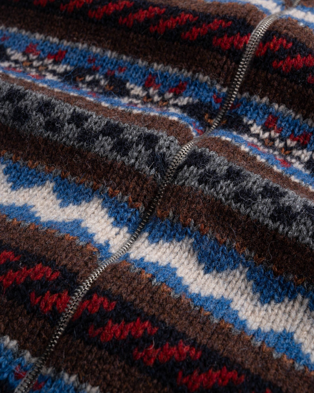 Gros plan sur le cardigan zippé Merci Paris Howlin' en laine vierge avec motifs Fair Isle colorés et géométriques