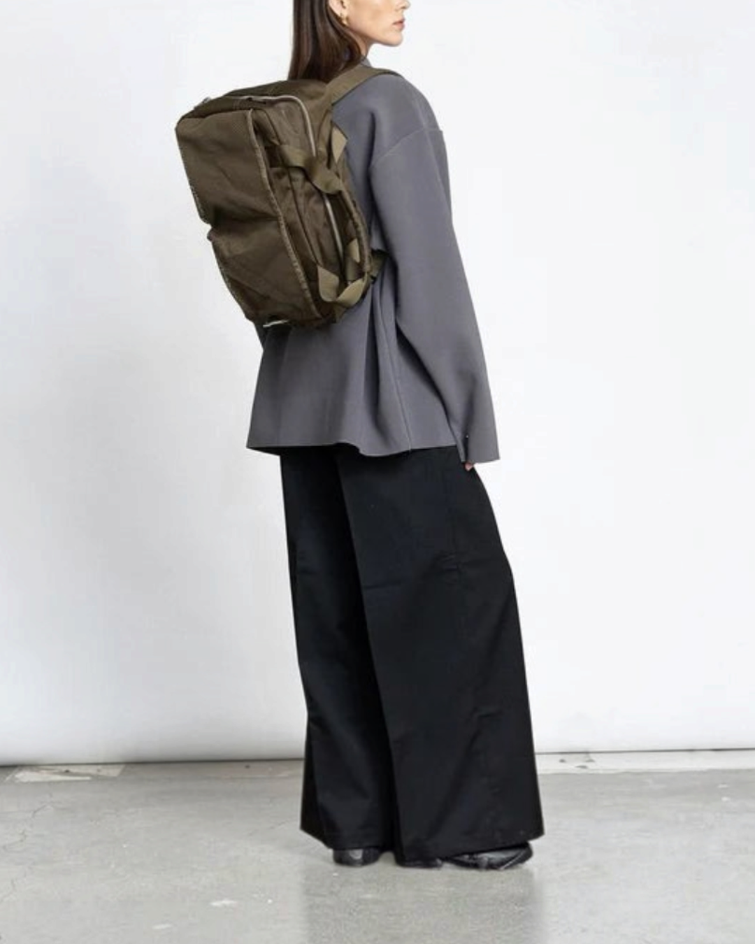 Modèle portant le sac de voyage Merci Paris AY Studios 18L en nylon recyclé kaki, design scandinave fonctionnel.