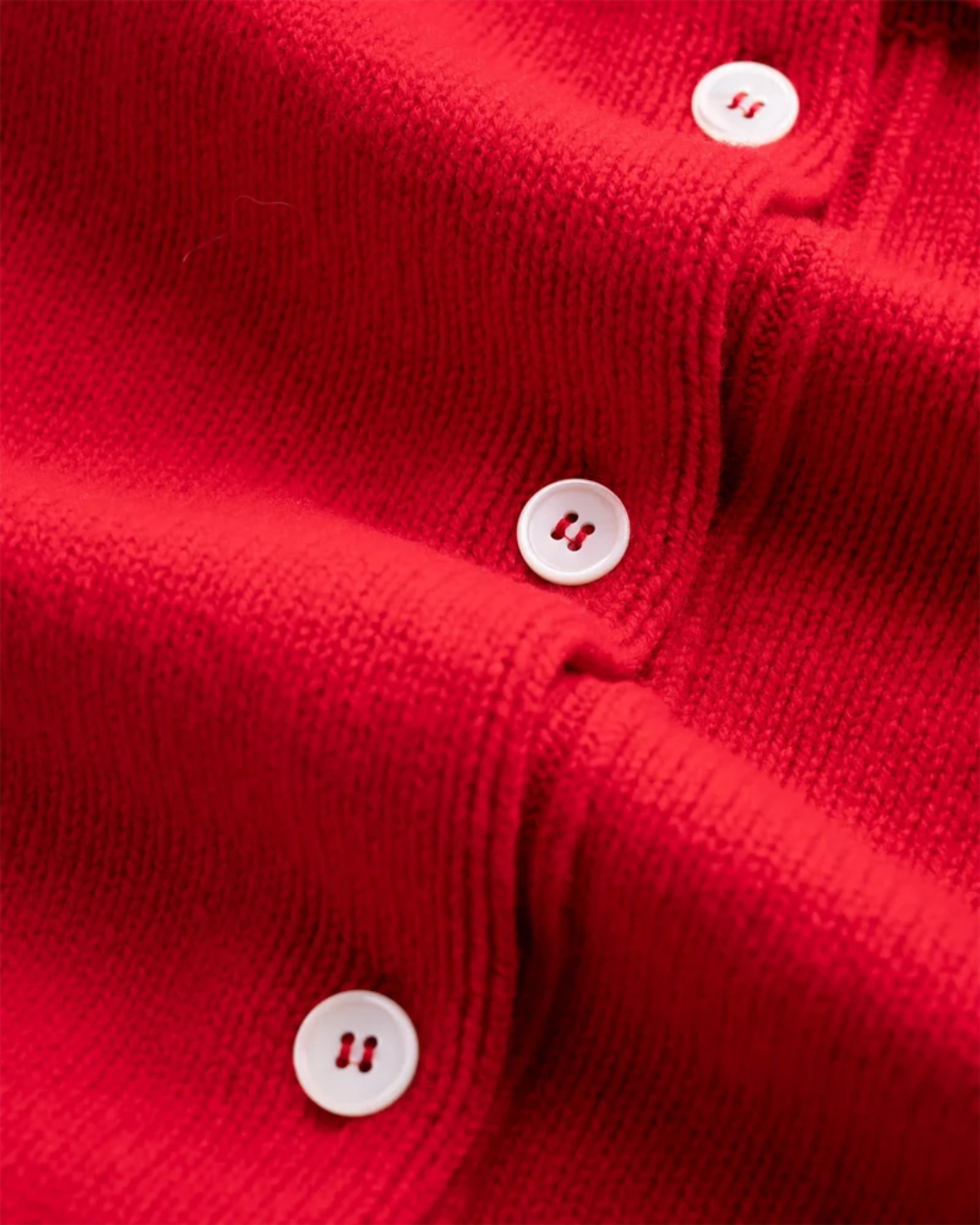 Gros plan sur le cardigan rouge Merci Paris Howlin' en laine d'agneau avec boutons en nacre contrastants