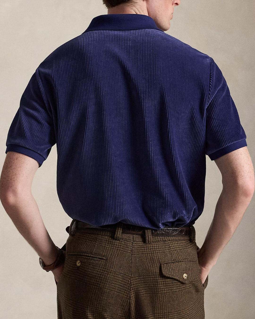 Vue arrière d'un homme portant un polo Merci Paris Ralph Lauren en velours côtelé bleu marine, coupe classique.